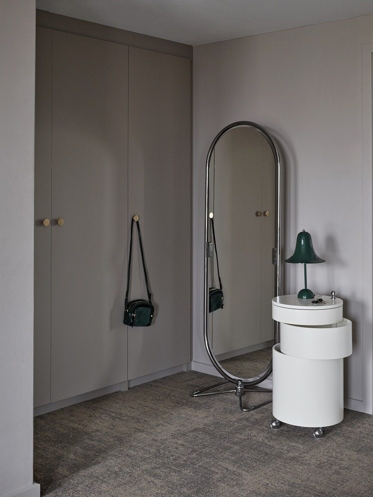 Grüne Pantop Tischleuchte von Verpan auf weißem Nachttisch neben einem Spiegel und Kleiderschrank.