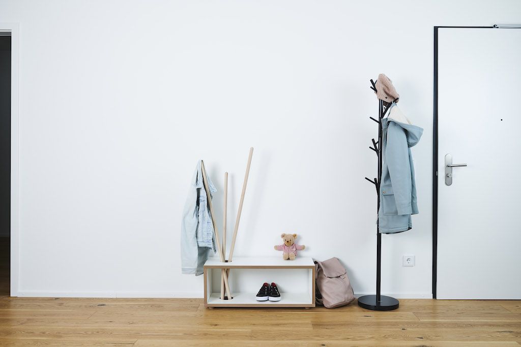 Tojo Kids Ordnung Kindergarderobe mit Jacken, Schuhen, Rucksack und Teddybär vor weißer Wand und Tür.