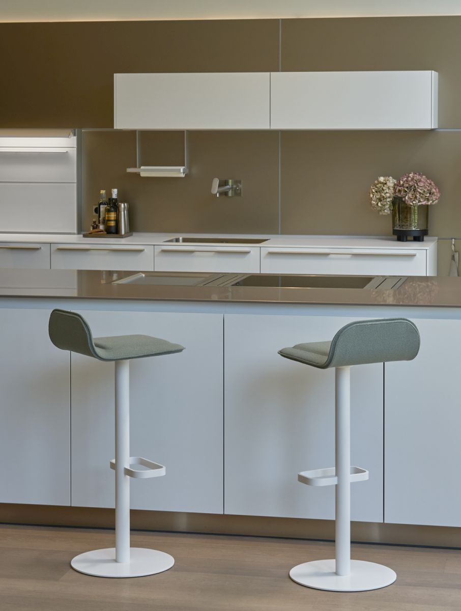 Zwei weiße Dave Barhocker mit salbeifarbenen Sitzpolstern vor einer modernen Küchenzeile.
