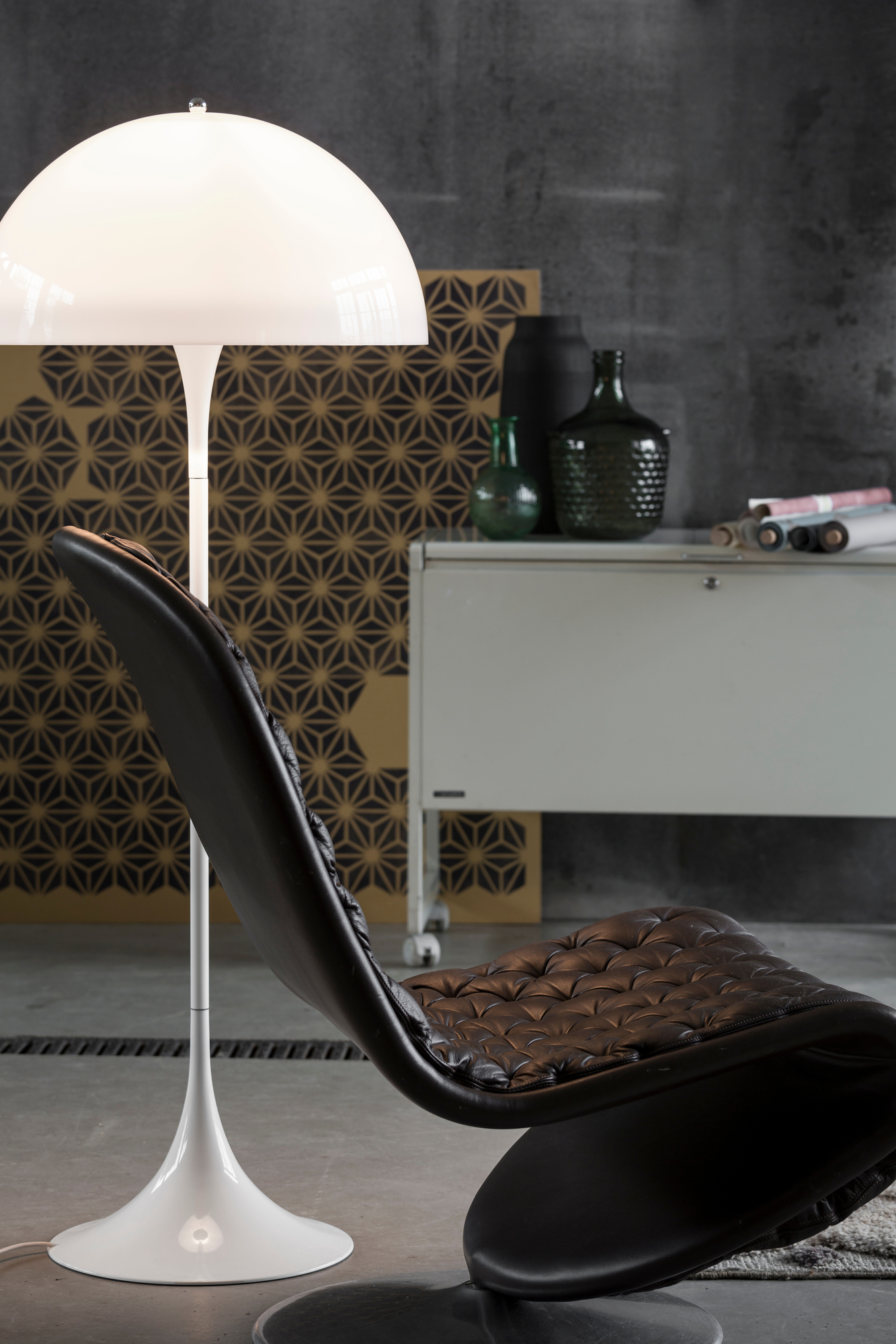 Panthella Stehleuchte von Louis Poulsen, weiße Designlampe neben schwarzem Sessel im Interieur.