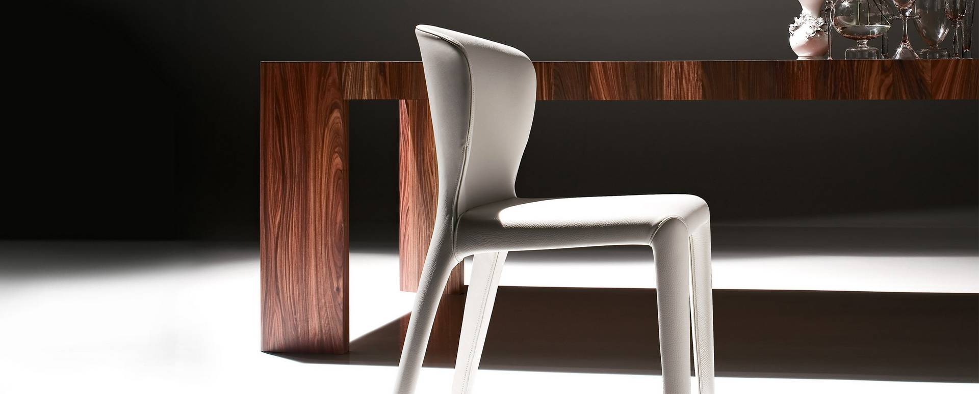 Weißer Cassina Hola Stuhl aus Leder vor einem Holztisch, modernes Möbeldesign.