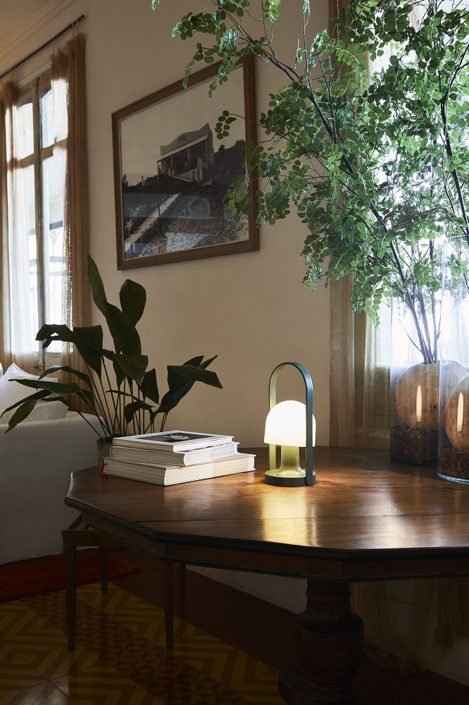 FollowMe LED Akkuleuchte von Marset auf Holztisch, moderne Tischleuchte, tragbare Lampe für Innenräume.