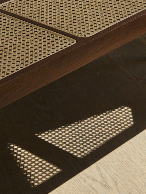 Detailaufnahme der NORR11 Le Roi Bank: Holzrahmen mit Wiener Geflecht und Lichtreflexionen.