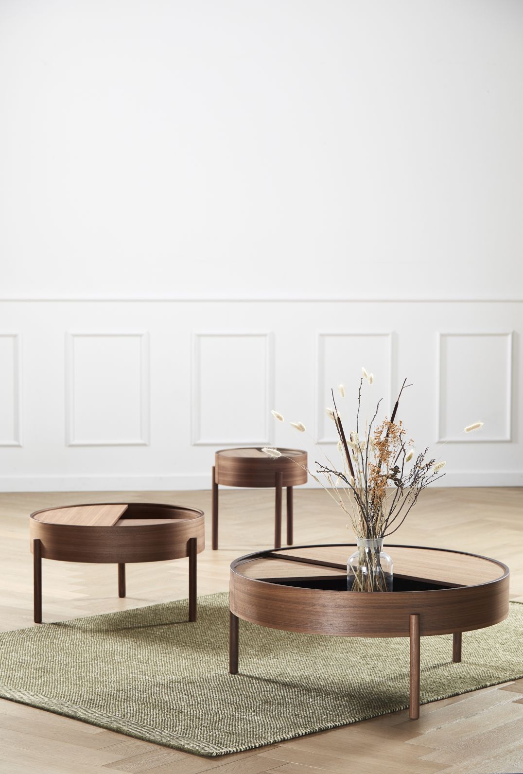 Drei Arc Coffee Tables von Woud aus Walnuss Holz in einem minimalistischen Wohnzimmer.