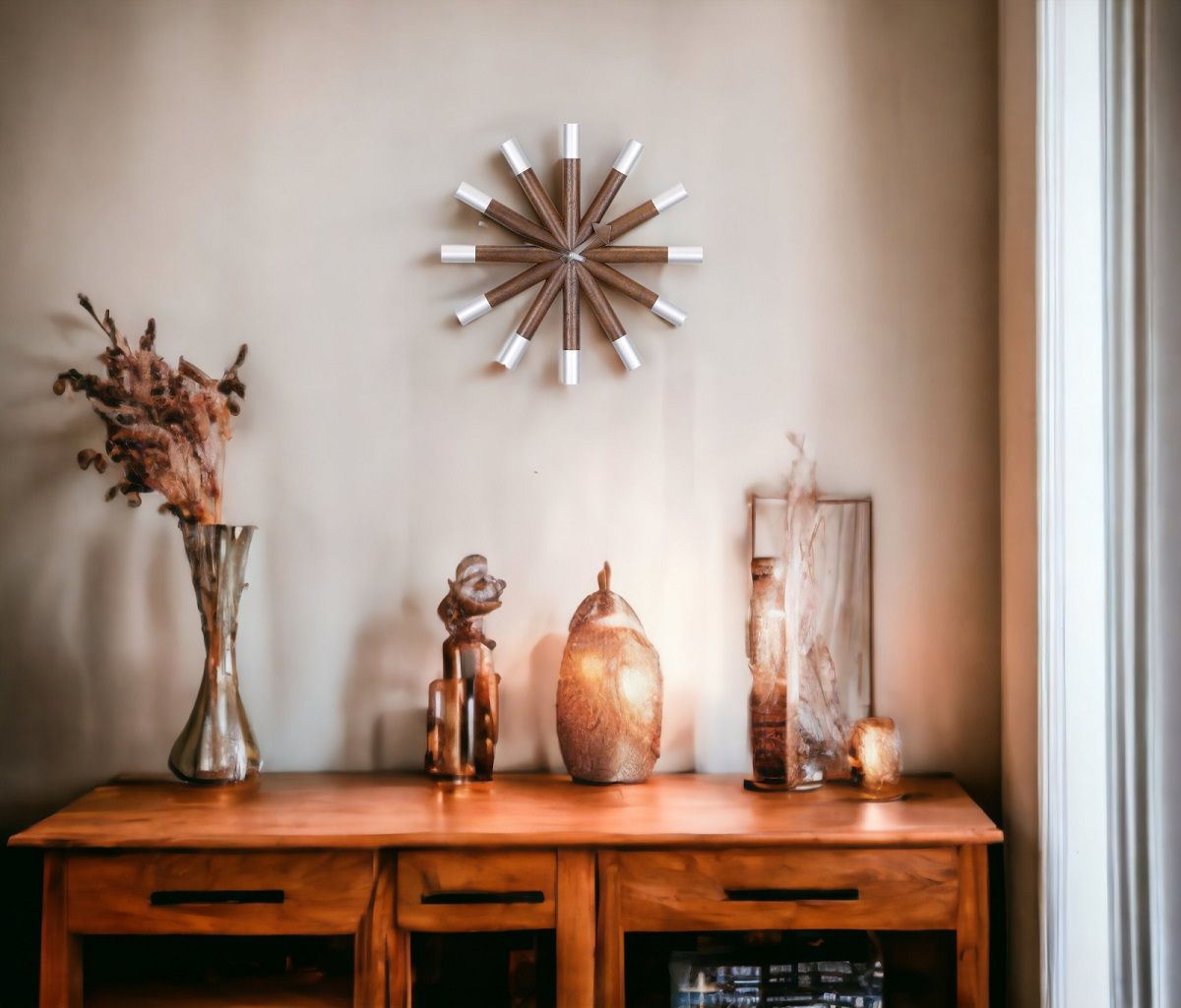 Vitra Wheel Clock Wanduhr aus Holz und Aluminium über Kommode mit Deko-Objekten.