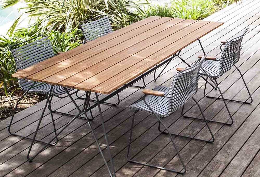 Houe Sketch Gartentisch aus Teakholz mit passenden Stühlen auf einer Holzterrasse im Freien.