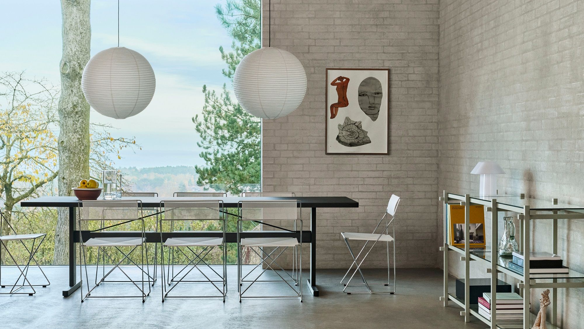 Helles Esszimmer mit Hay Regal, Esstisch, Stühlen und Papierlampen vor großem Fenster.