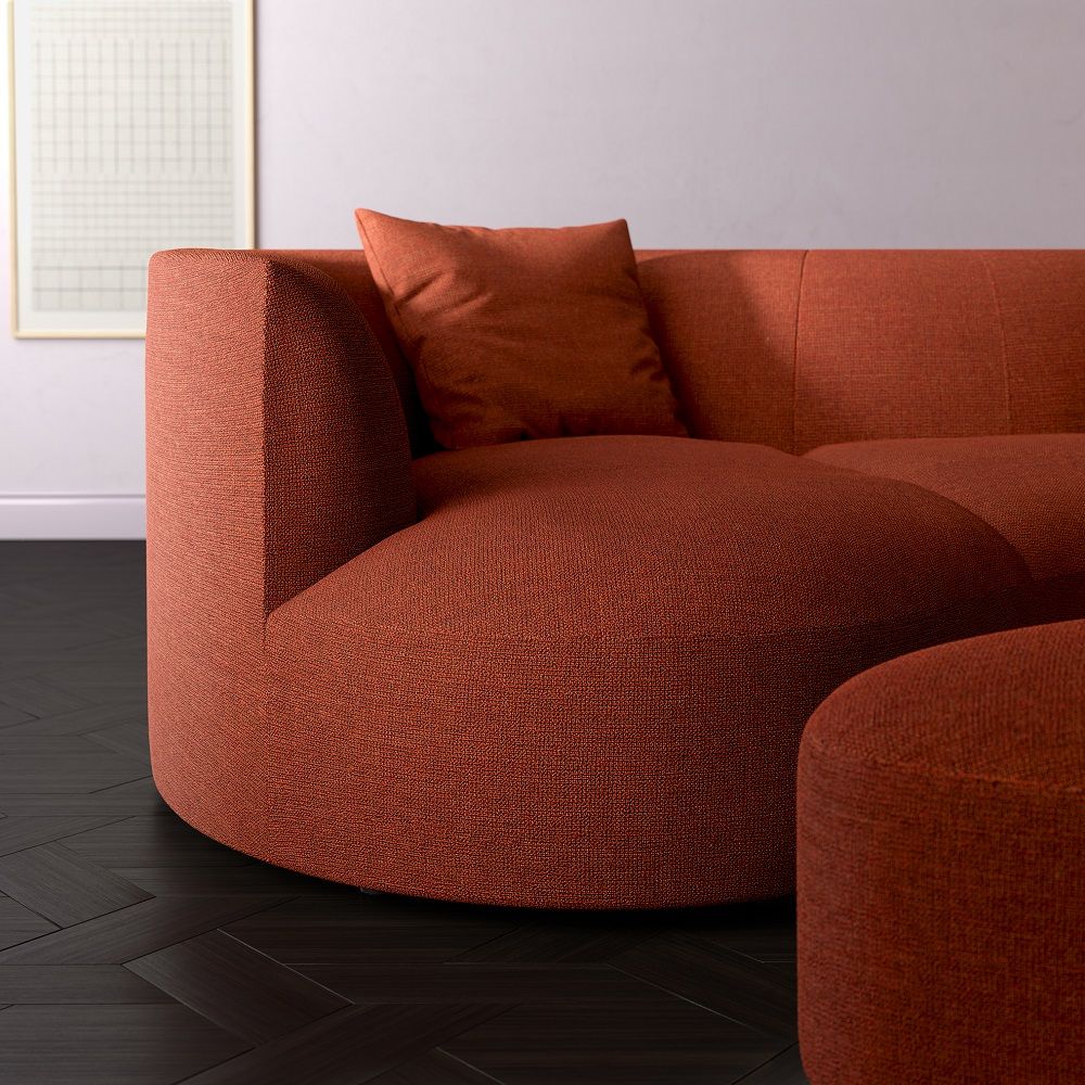 Nahaufnahme des Siwa Sofas mit Liege in warmem, strukturiertem Rotton und passendem Kissen.