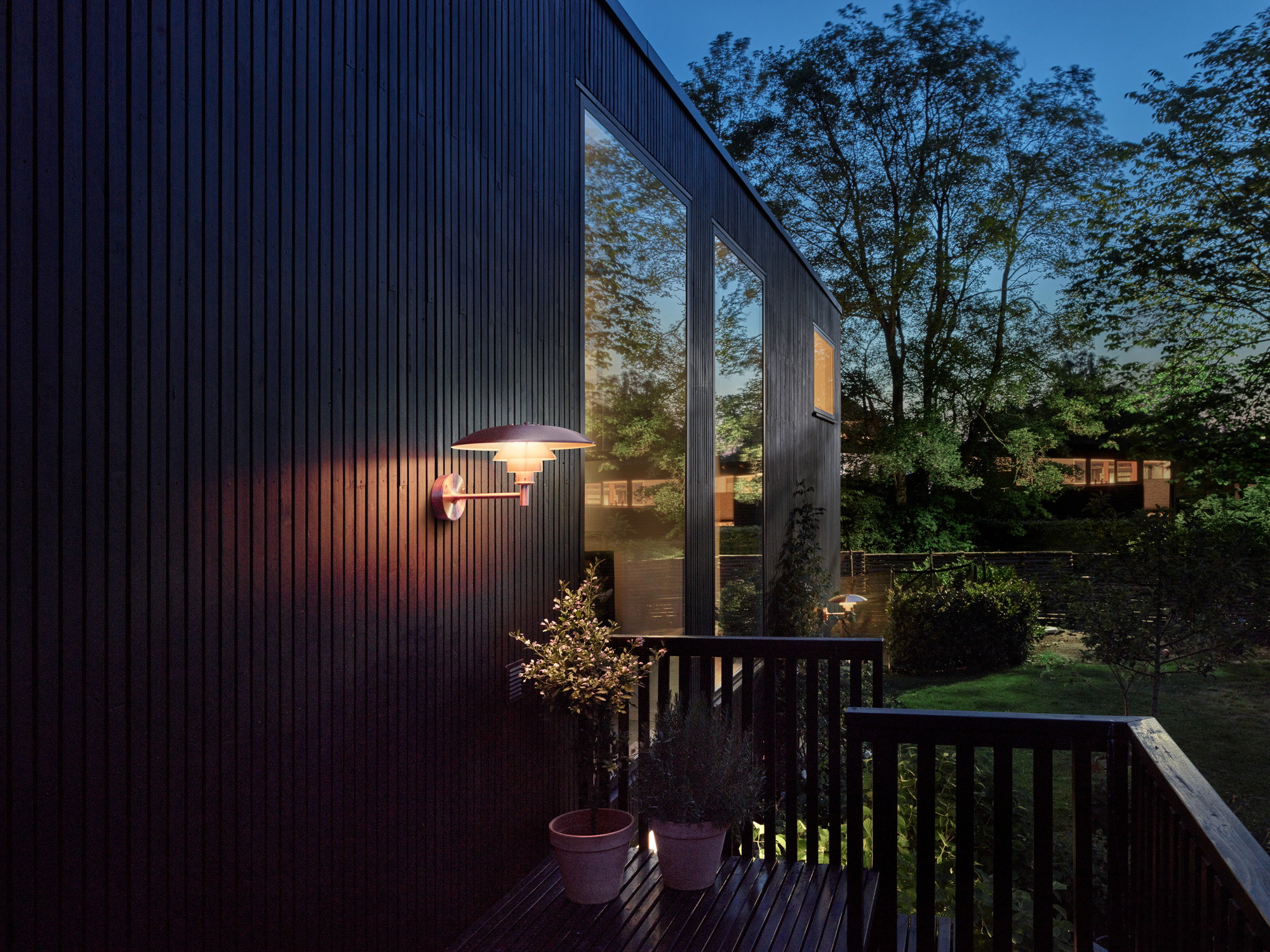 PH Wandleuchte von Louis Poulsen an dunkler Hauswand im Außenbereich, stimmungsvolle Beleuchtung.
