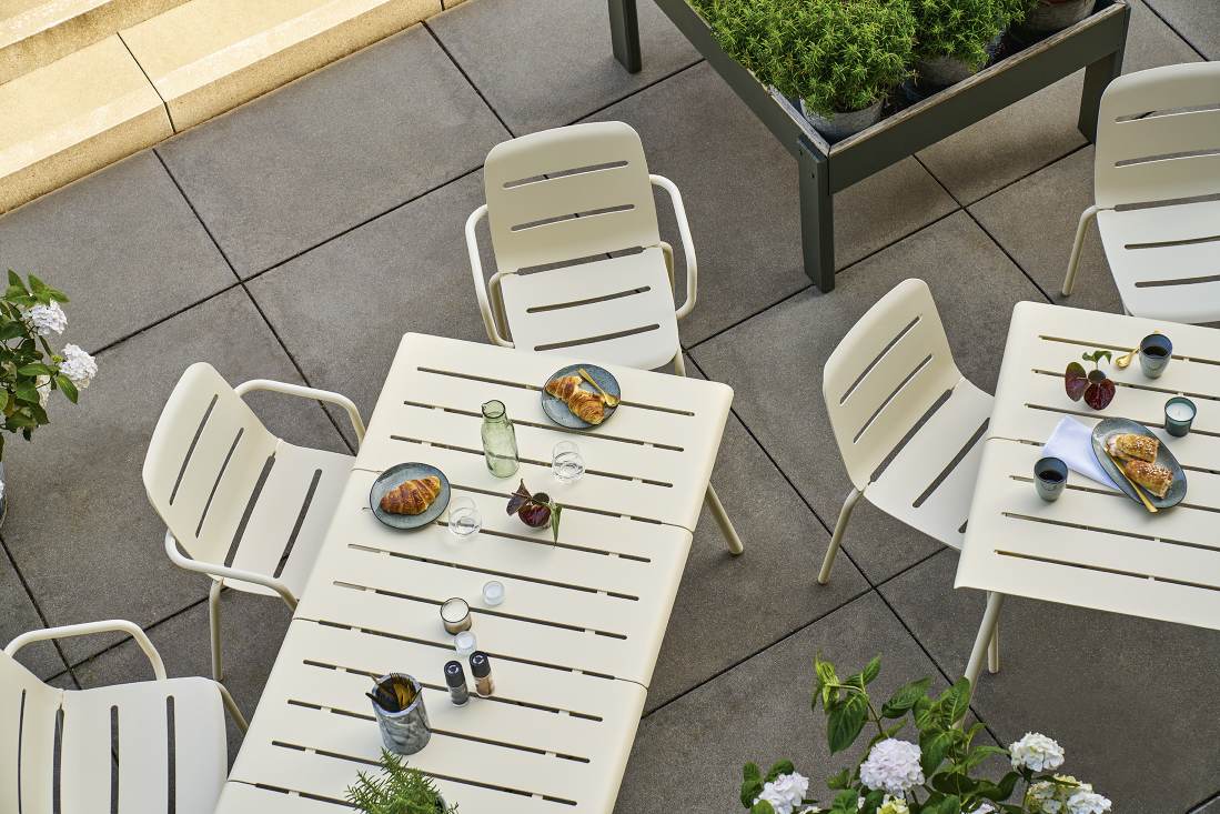 Draufsicht: Weishäupl Vapio Sessel in Beige mit passendem Gartentisch und Frühstücksgedecken auf einer Terrasse.