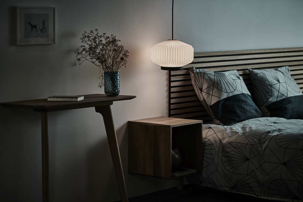 Shibui Pendelleuchte von Le Klint: Elegante, weiße Hängelampe im Schlafzimmer neben Nachttisch und Bett.