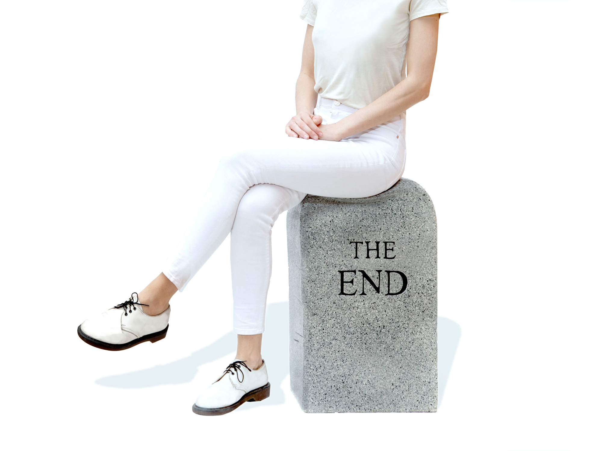 Frau sitzt auf grauem "The End" Hocker von Gufram, originelles Möbelstück für Wohnzimmer und Büro.