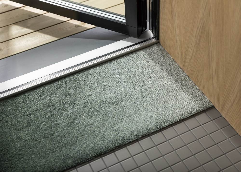 Nahaufnahme der Dis Heymat Ocean Fußmatte im Eingangsbereich, ideal für drinnen und draußen.