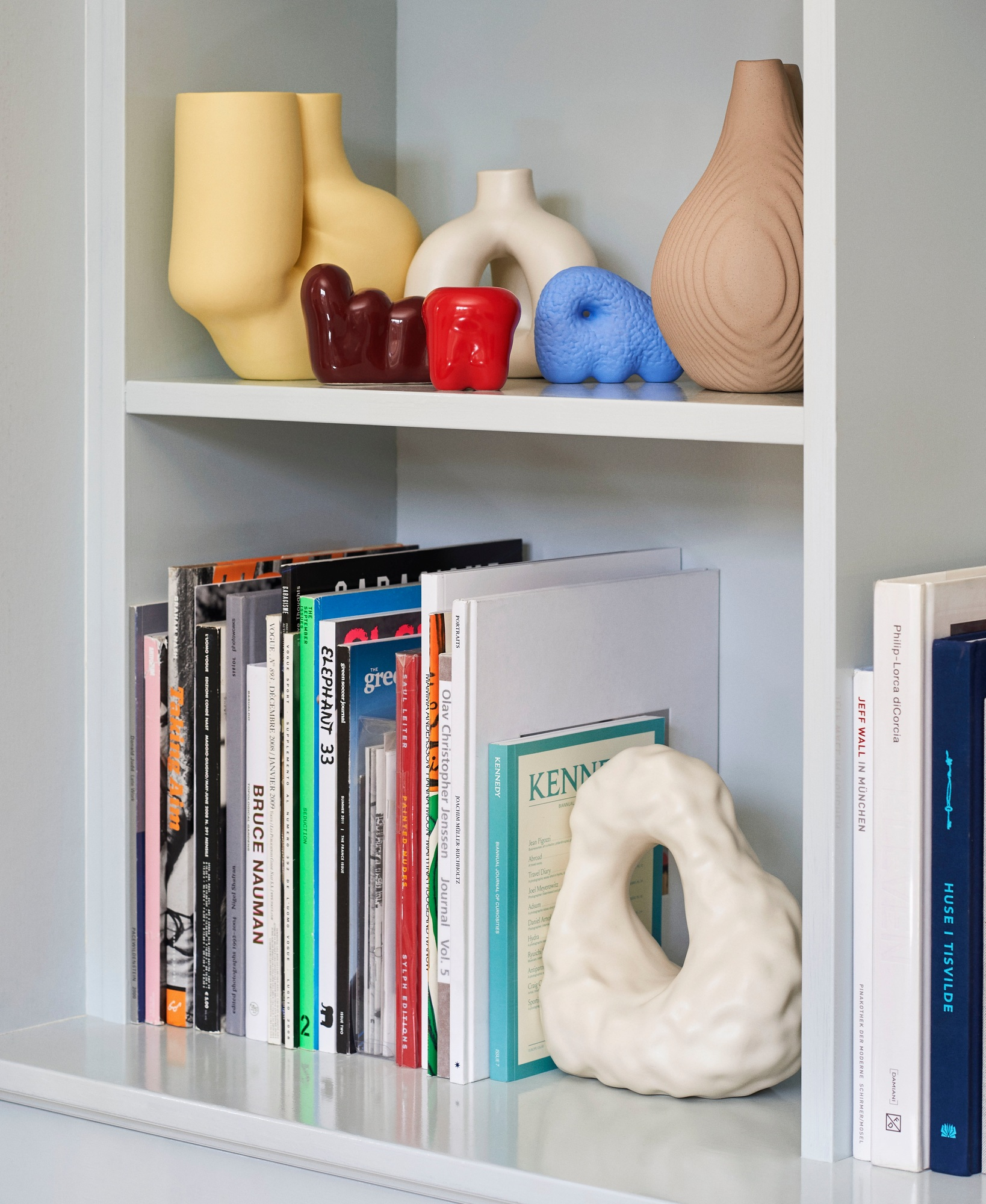 Regal mit Büchern und dekorativen Objekten, darunter eine weiße W&S Boulder Bookend Buchstütze von Hay.