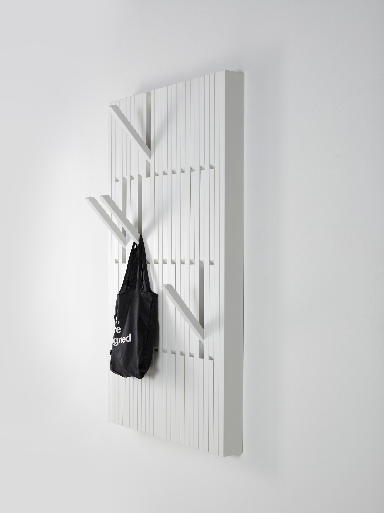 Weiße Piano Wandgarderobe mit Haken und schwarzer Tasche, moderne Garderobenlösung für Flur und Eingangsbereich.
