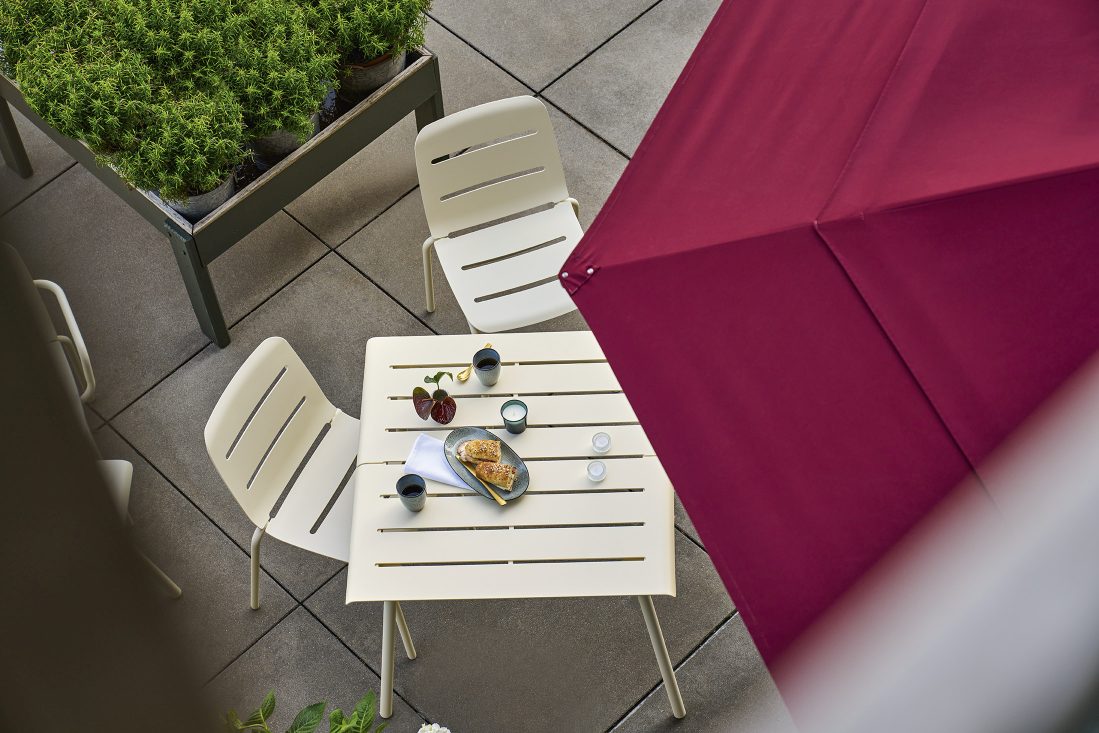 Draufsicht auf eine Outdoor-Szene mit Weishäupl Vapio Stühlen und Tisch, gedeckt mit Speisen und Getränken.