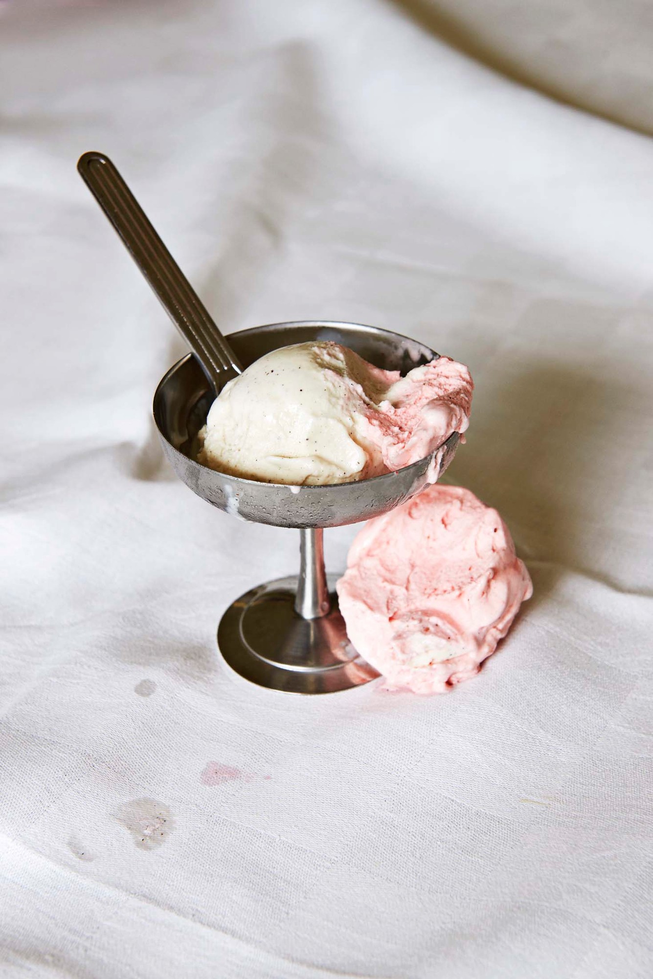 Italian Ice Cup Eisbecher: Metallener Eisbecher mit Vanille- und Erdbeereis, Löffel und Eisresten.