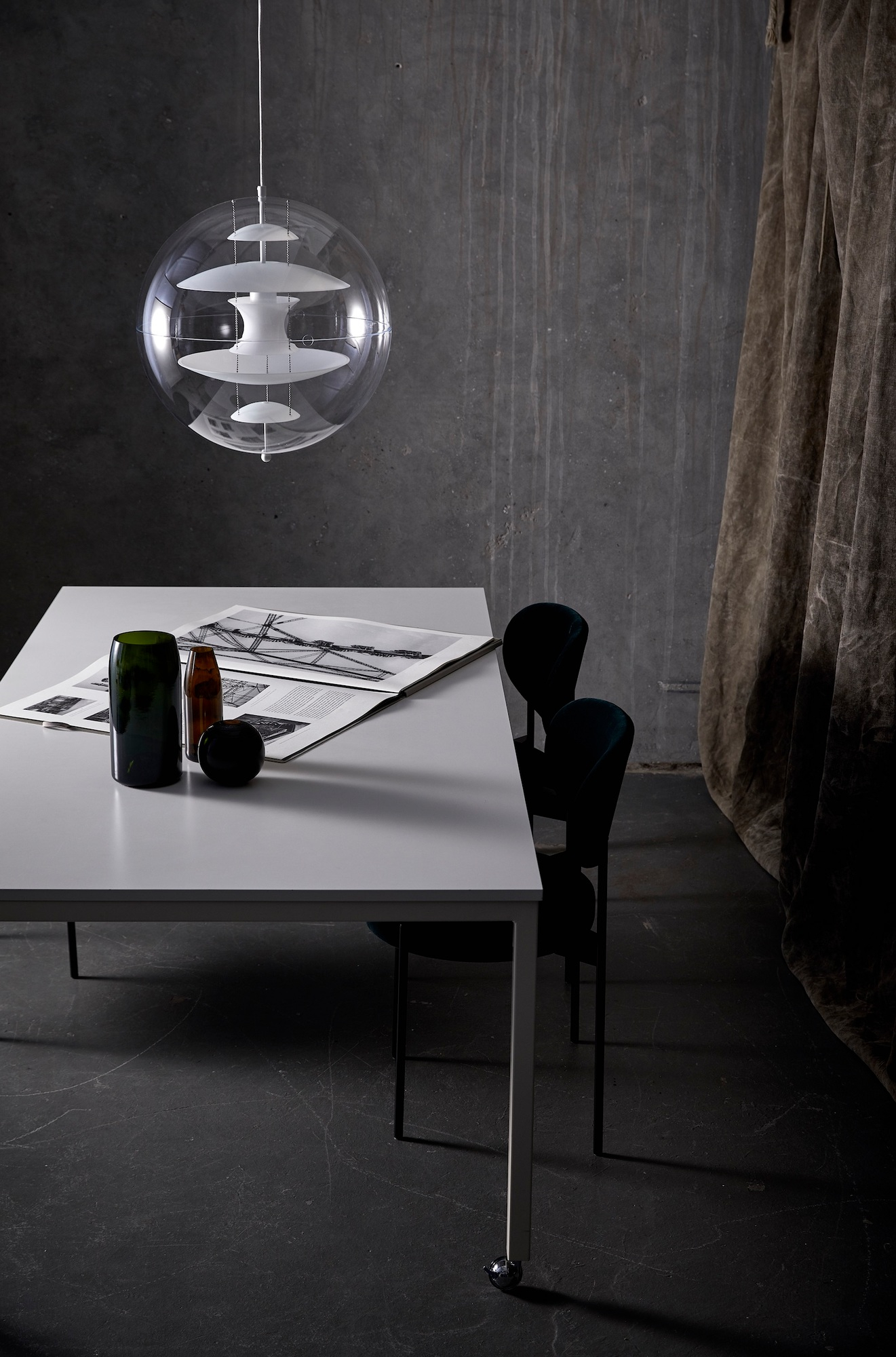 VP Globe Pendelleuchte von Verpan über Esstisch mit Dekoration und Stühlen vor grauer Wand.