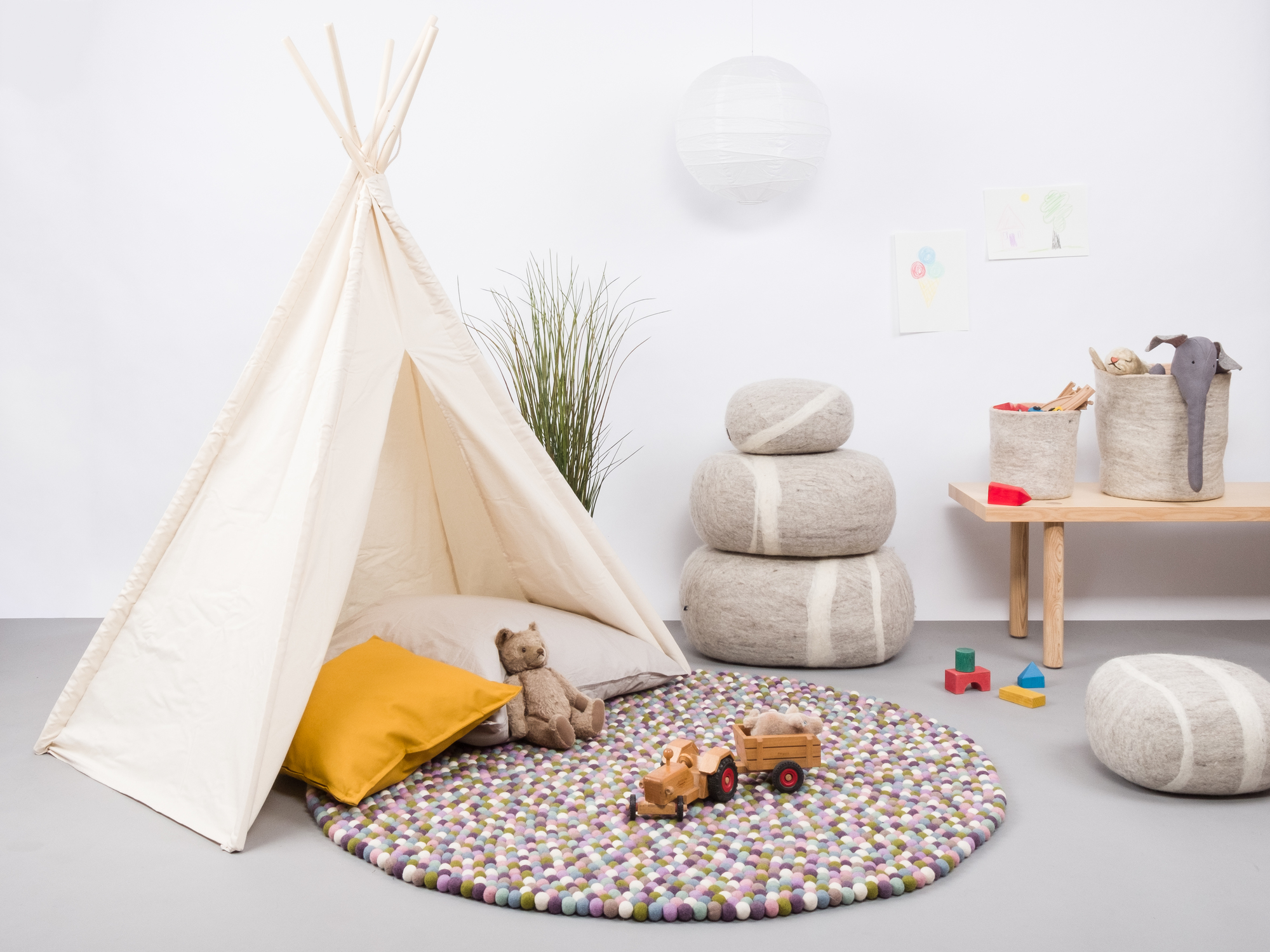 Runder Filzkugel Teppich im Kinderzimmer mit Spielzeug und Tipi-Zelt.