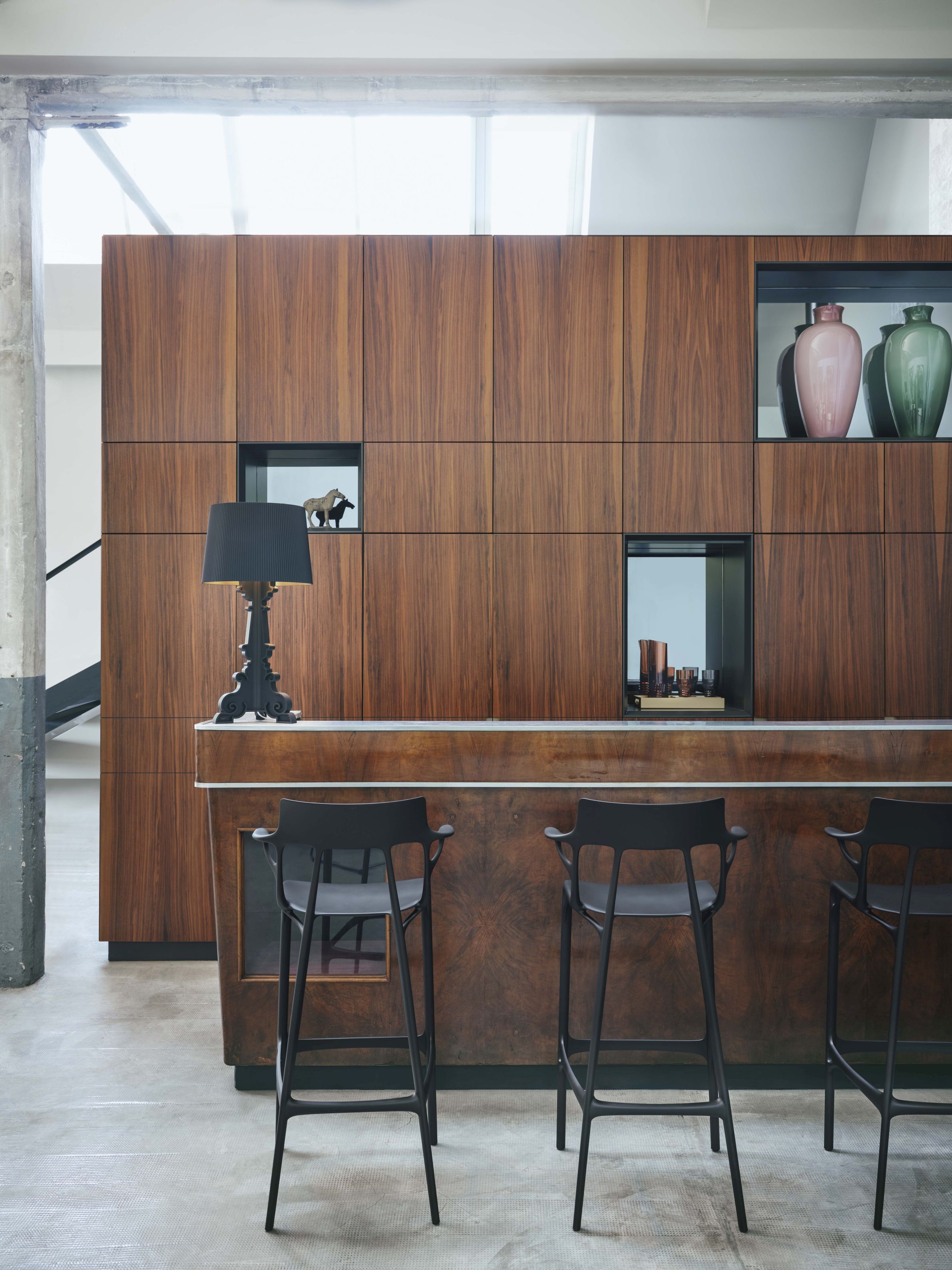 Bourgie Tischleuchte von Kartell in Schwarz auf einer Bar mit Hockern. Designleuchte.