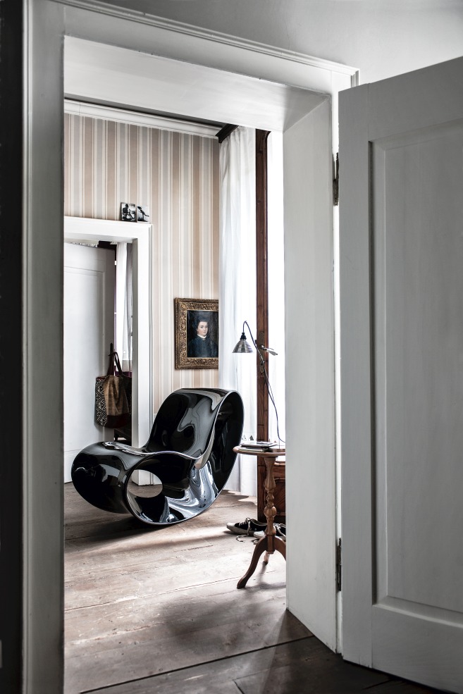 VOIDO Schaukelstuhl von Magis, modernes Designobjekt in glänzendem Schwarz, gesehen durch eine offene Tür in einem stilvollen Interieur.