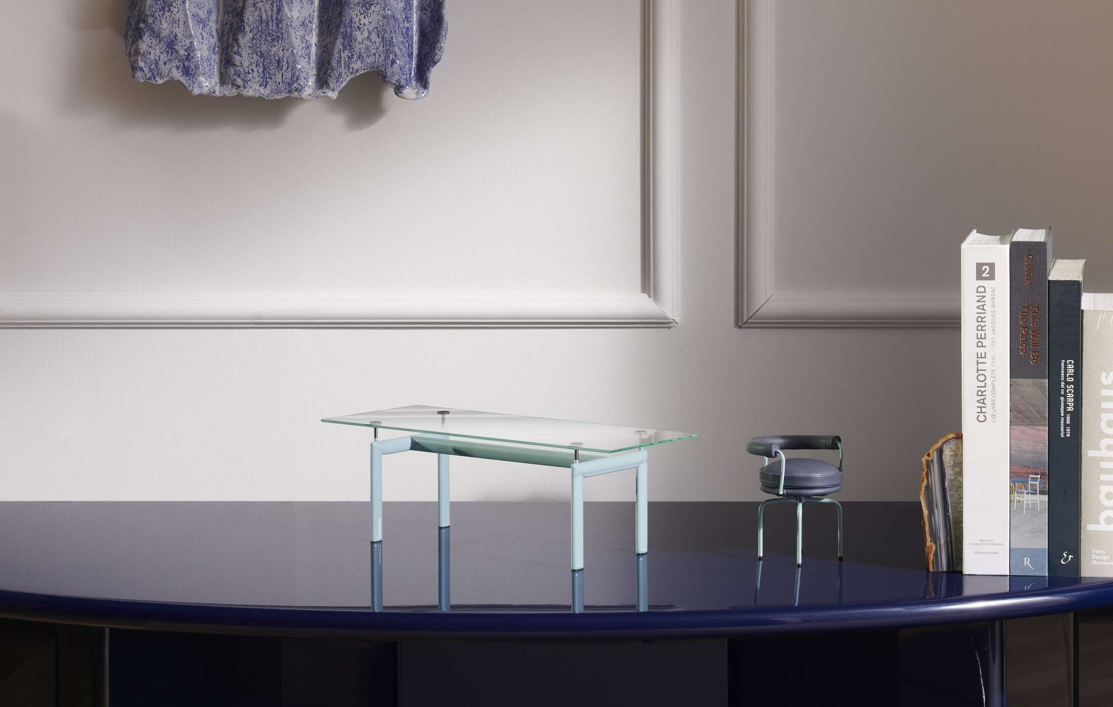Nahaufnahme des Cassina Le Miniature Table en Tube Miniaturtischs mit Glasplatte und blauem Gestell.