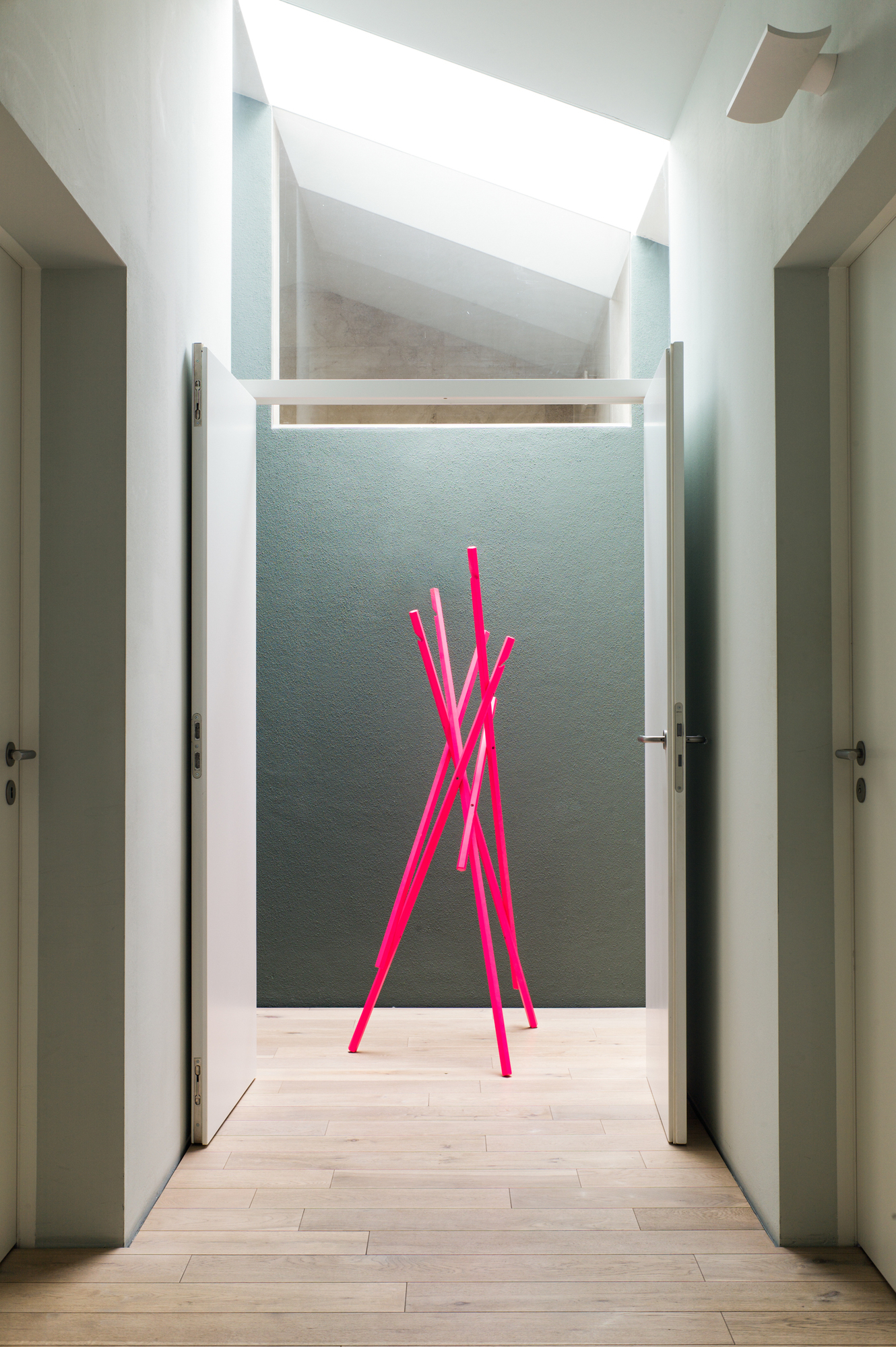 Pinker Sticks Garderobenständer von Schönbuch im Flur mit Holzboden und Tageslicht. Design Garderobe für Jacken.