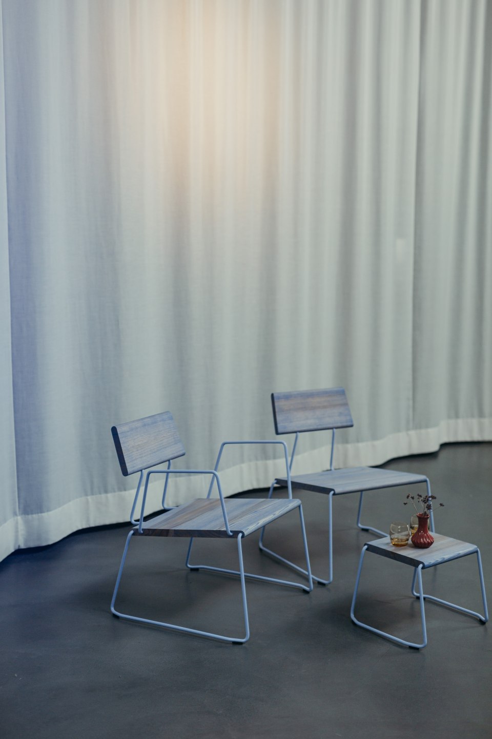 Zwei D:007 Loungechairs Ultraviolett von Fuchs & Habicht mit passendem Beistelltisch vor Vorhang.