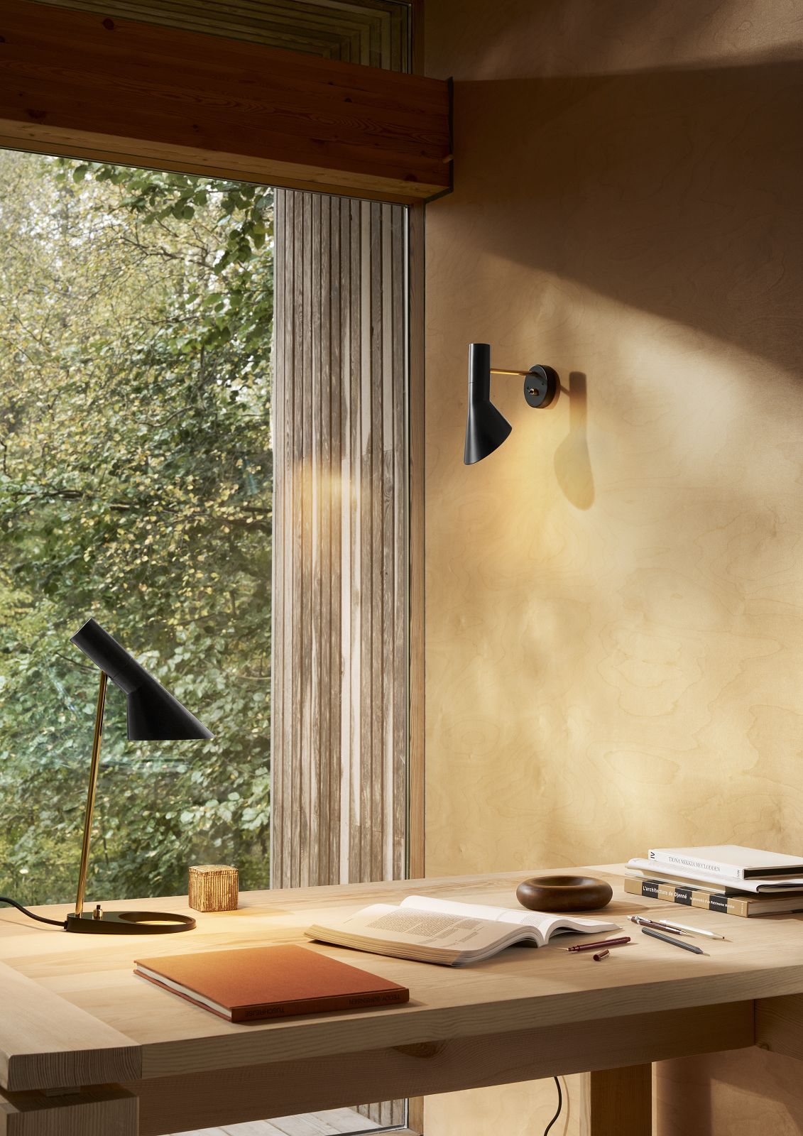 AJ Mini Tischleuchte von Louis Poulsen in Schwarz und Gold auf einem Schreibtisch.