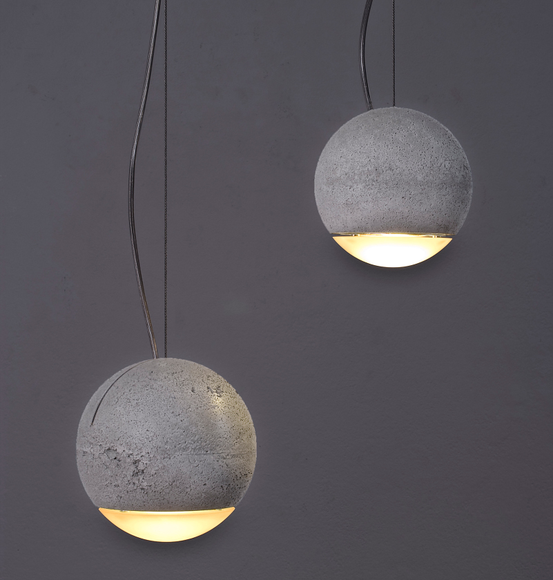 Zwei Trabant 2 Pendelleuchten von Tecnolumen, kugelförmig aus Beton, mit warmweißem Licht nach unten.