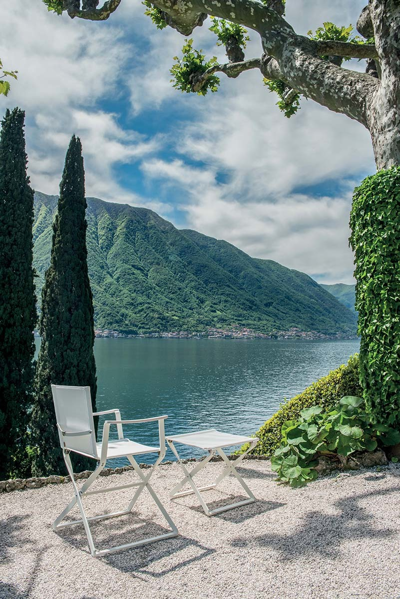 Weißer Ciak Regiestuhl von Emu mit Beistelltisch im Freien vor malerischer Seekulisse.