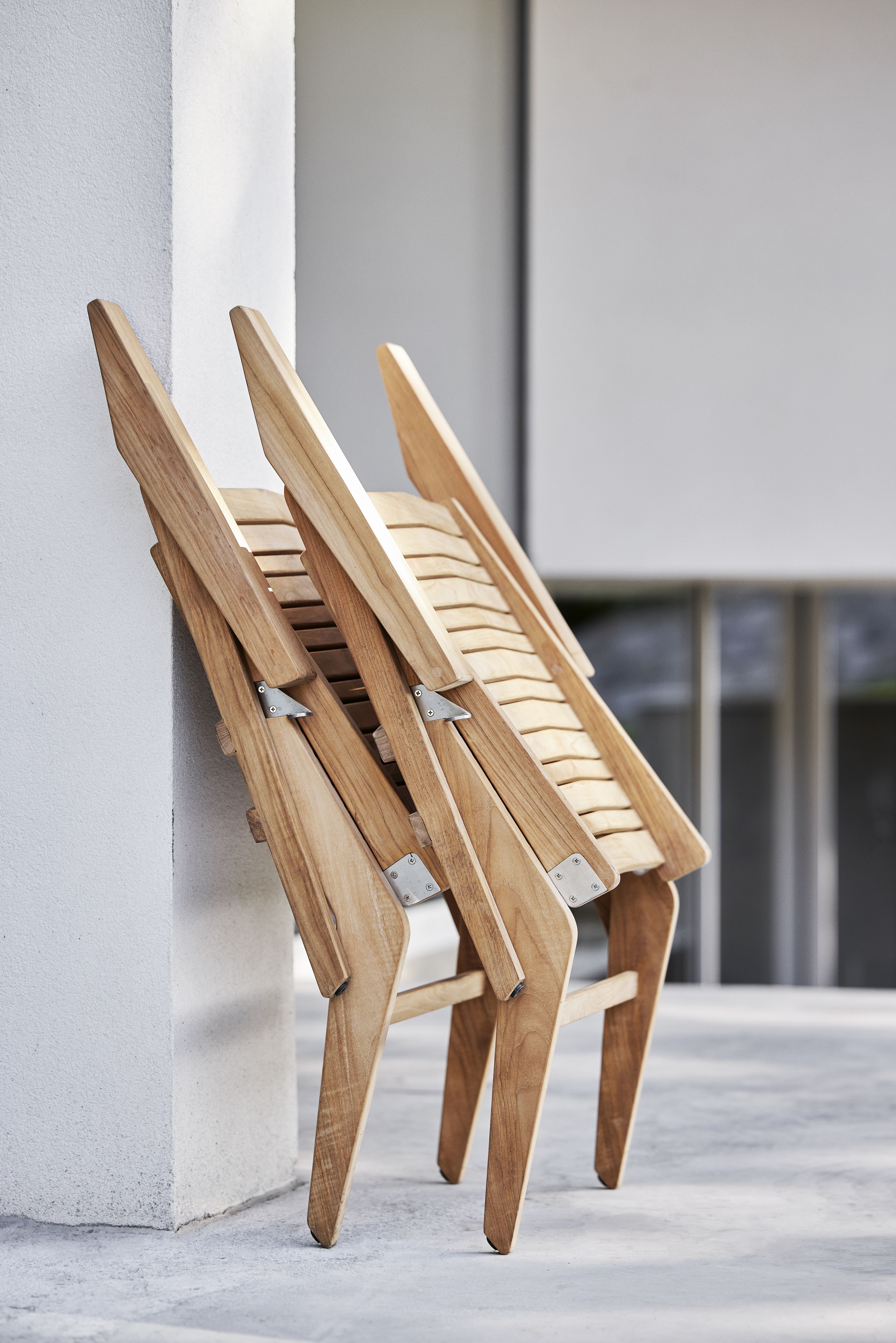 Gestapelte Cane-Line Flip Loungesessel aus Teakholz, ideal für Garten, Terrasse und Balkon.