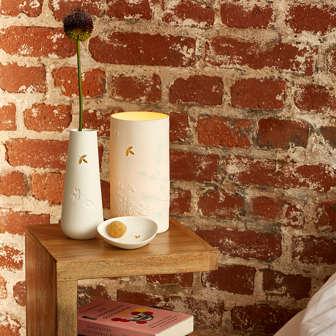 Nahaufnahme der Räder Porzellangeschichten Leuchte, Vase und Schale mit Goldblatt-Dekor auf Nachttisch.