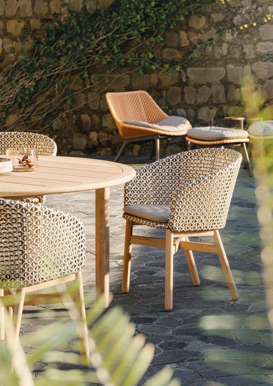 Nahaufnahme des Dedon Mbrace Lounge Chairs mit Sitzkissen, Teil eines Outdoor-Essbereichs.