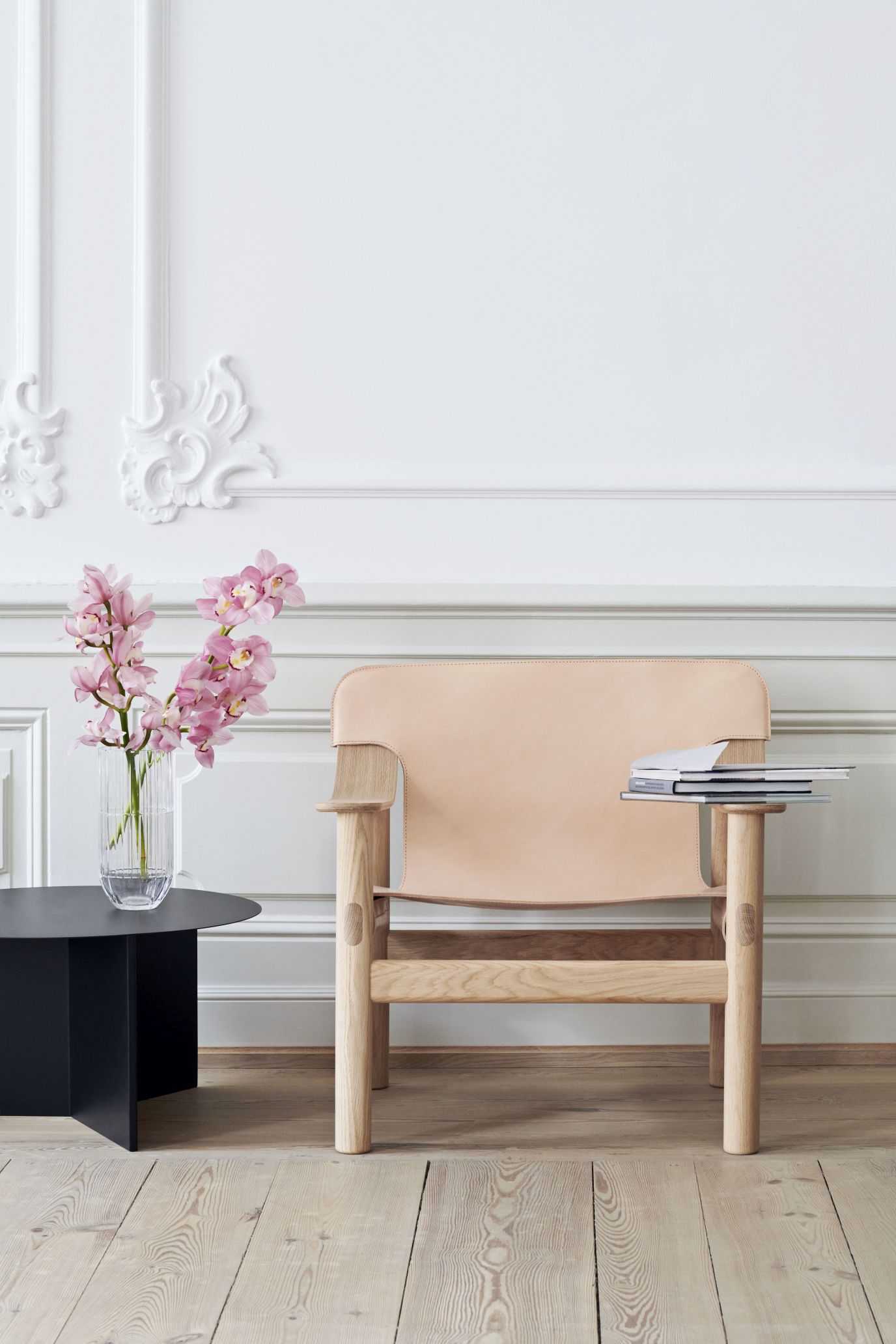 Schwarzer Slit Table Round Beistelltisch von Hay neben einem Sessel mit Blumen in modernem Interieur.
