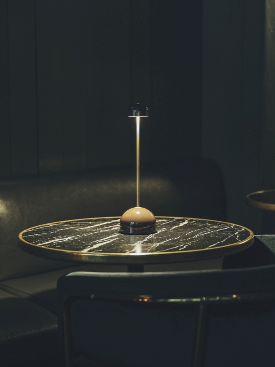 Sips Akkuleuchte von Marset in Weiß/Silber auf einem Marmortisch, stimmungsvolle Tischleuchte.