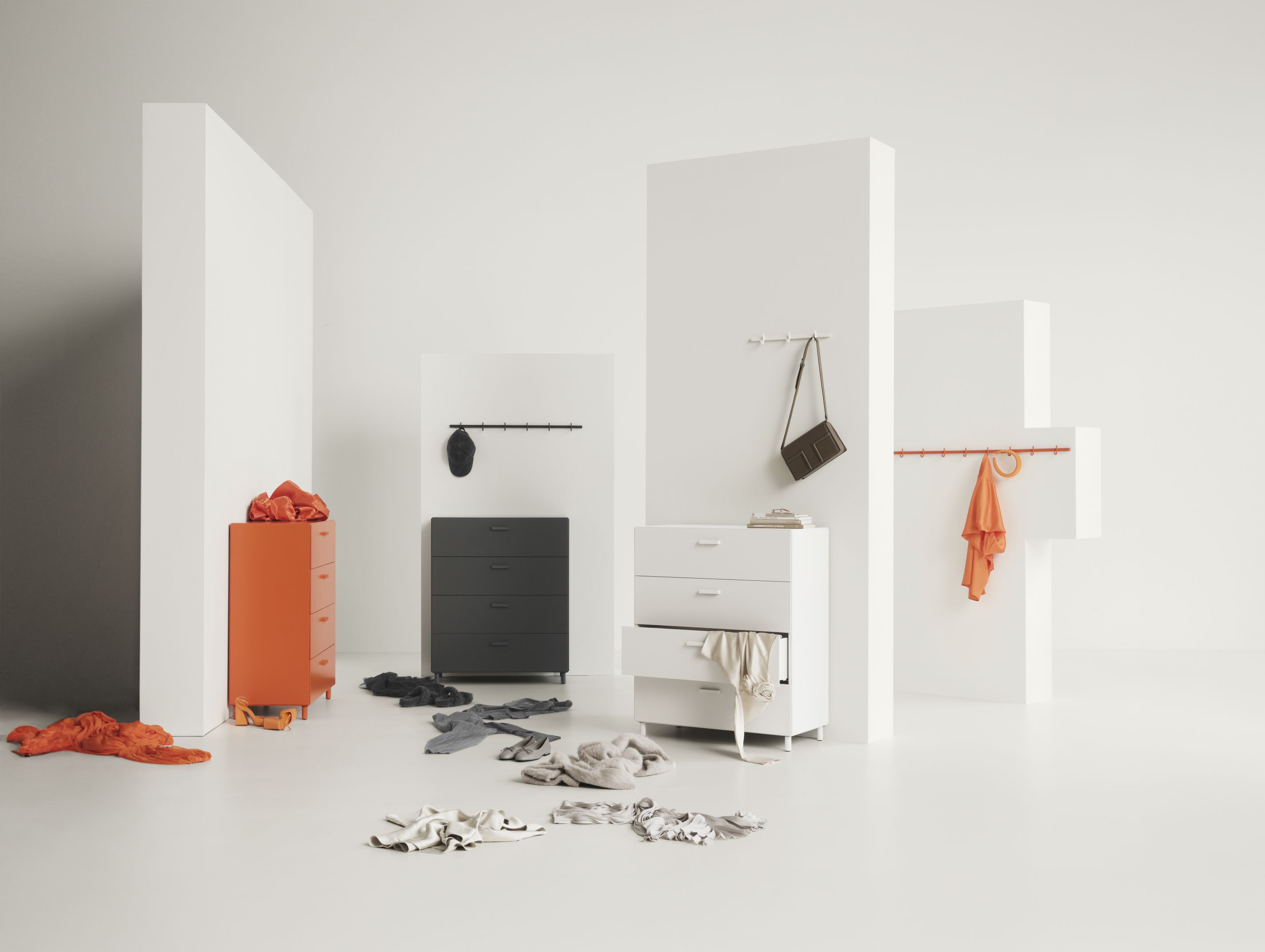 Graue String Furniture Relief Hakenleiste mit Kleidung und Accessoires an verschiedenen Kommoden und Haken.