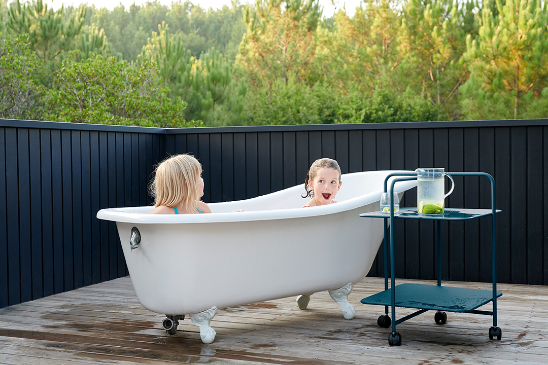 Alfred Beistelltisch von Fermob neben Badewanne mit Kindern im Freien. Outdoor Möbel für Garten und Terrasse.