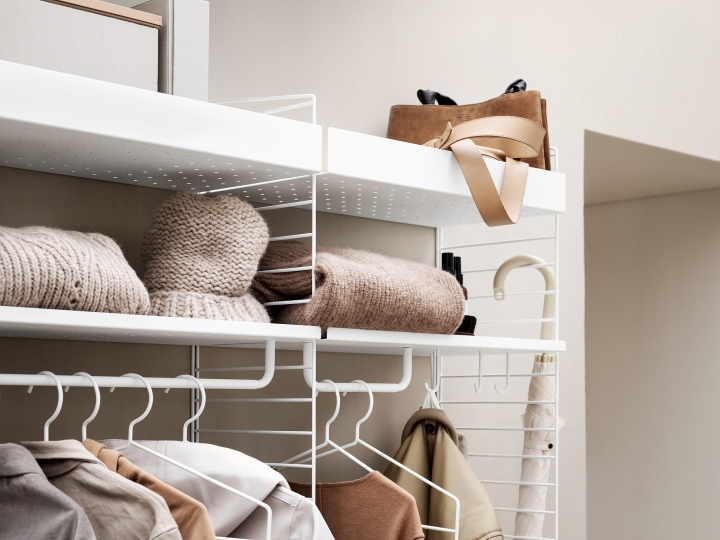 Detailaufnahme des Flur KONFIGURATIONEN String Regalsystems mit Kleidung, Tasche und Accessoires.