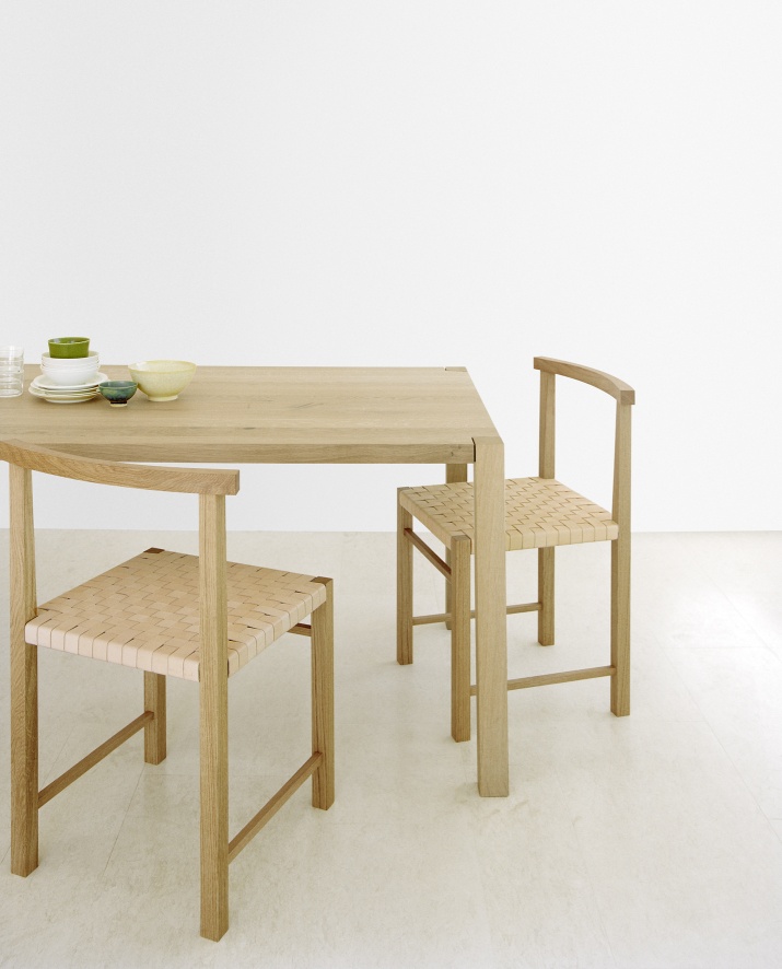 TA19 Sloane Tisch von e15 aus hellem Holz mit zwei Stühlen und Geschirr.