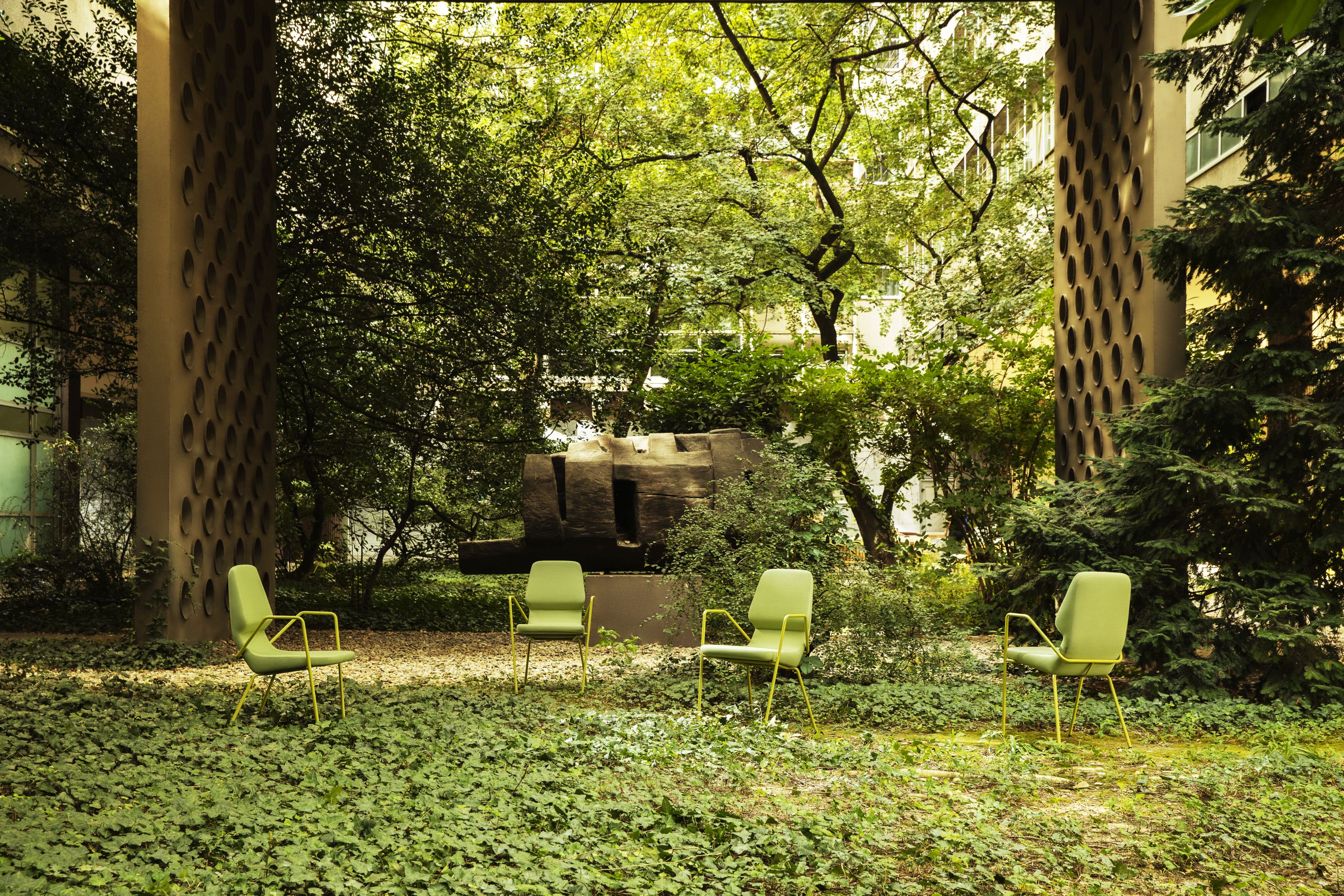 Vier grüne Prostoria Oblique Sessel im Freien, umgeben von üppigem Grün. Outdoor Sessel für Garten und Terrasse.