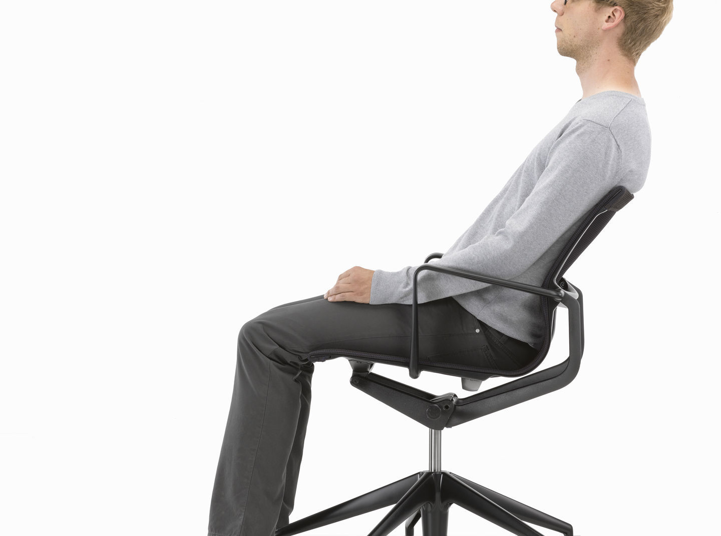 Mann sitzt auf einem schwarzen Physix Bürodrehstuhl von Vitra, Seitenansicht. Ergonomischer Bürostuhl mit Armlehnen.