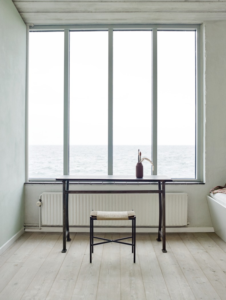 Vent Hocker von Skagerak by Fritz Hansen vor Fenster mit Meerblick, minimalistisches Design.