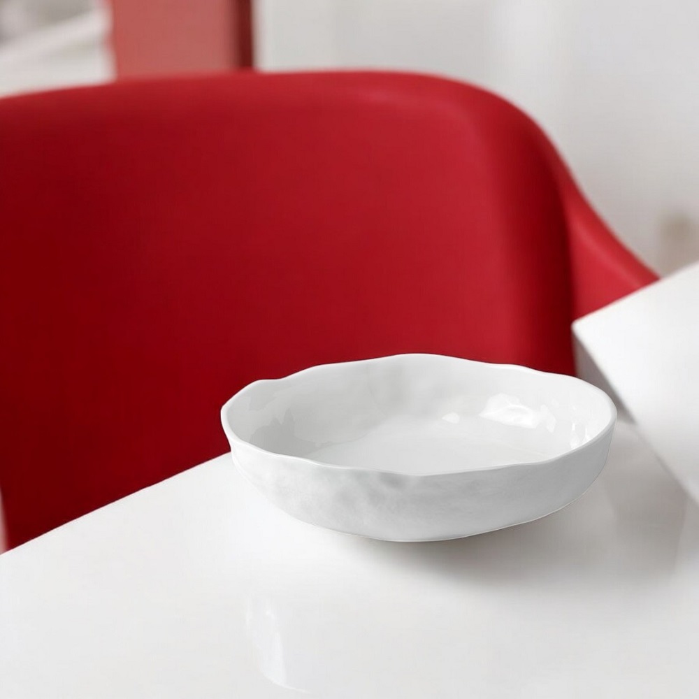 Weiße Räder Porzellan Schale, Genuss Schale, auf weißer Oberfläche vor rotem Stuhl.