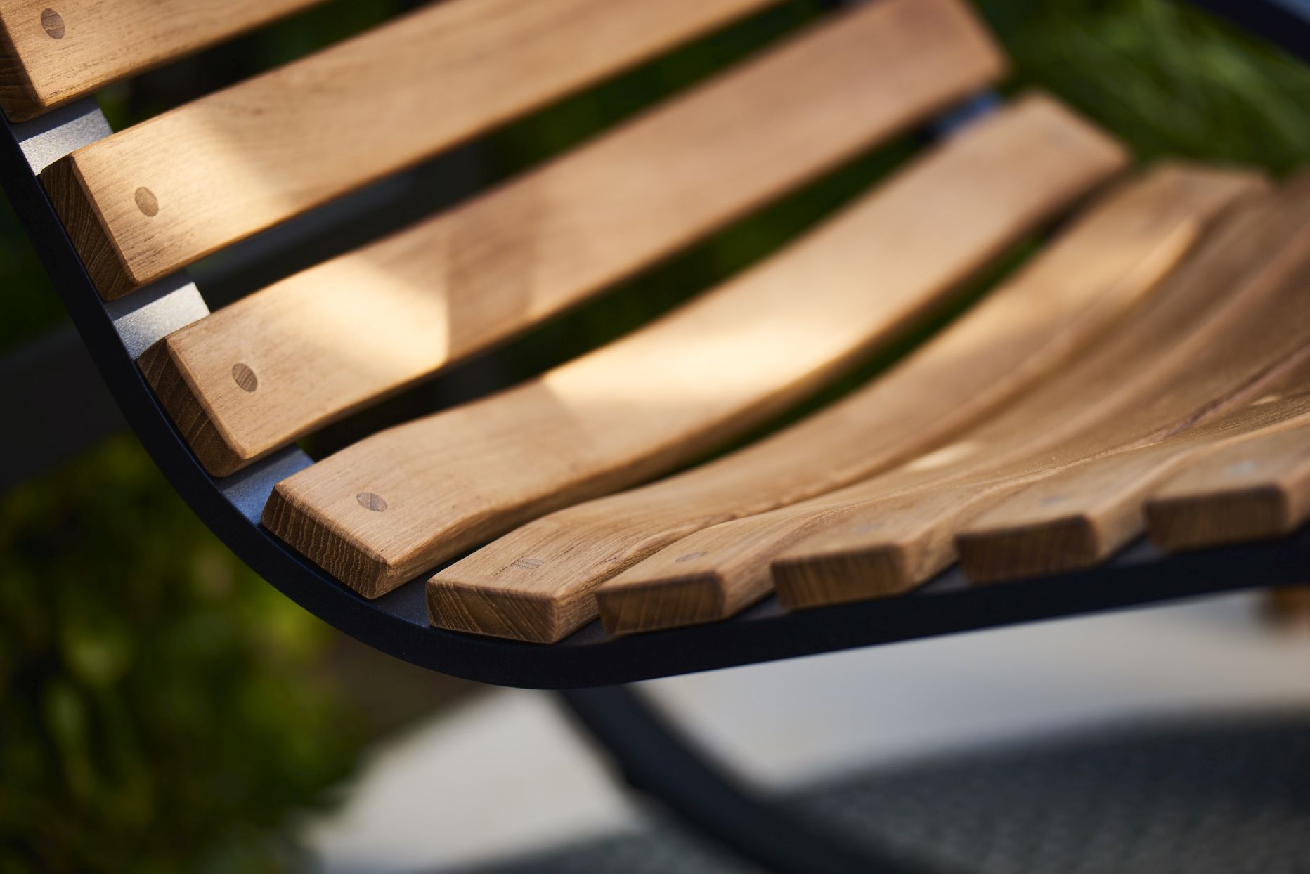 Detailaufnahme: Holzlatten und schwarzes Gestell des Cane-Line Parc Schaukelstuhls für Garten und Terrasse.