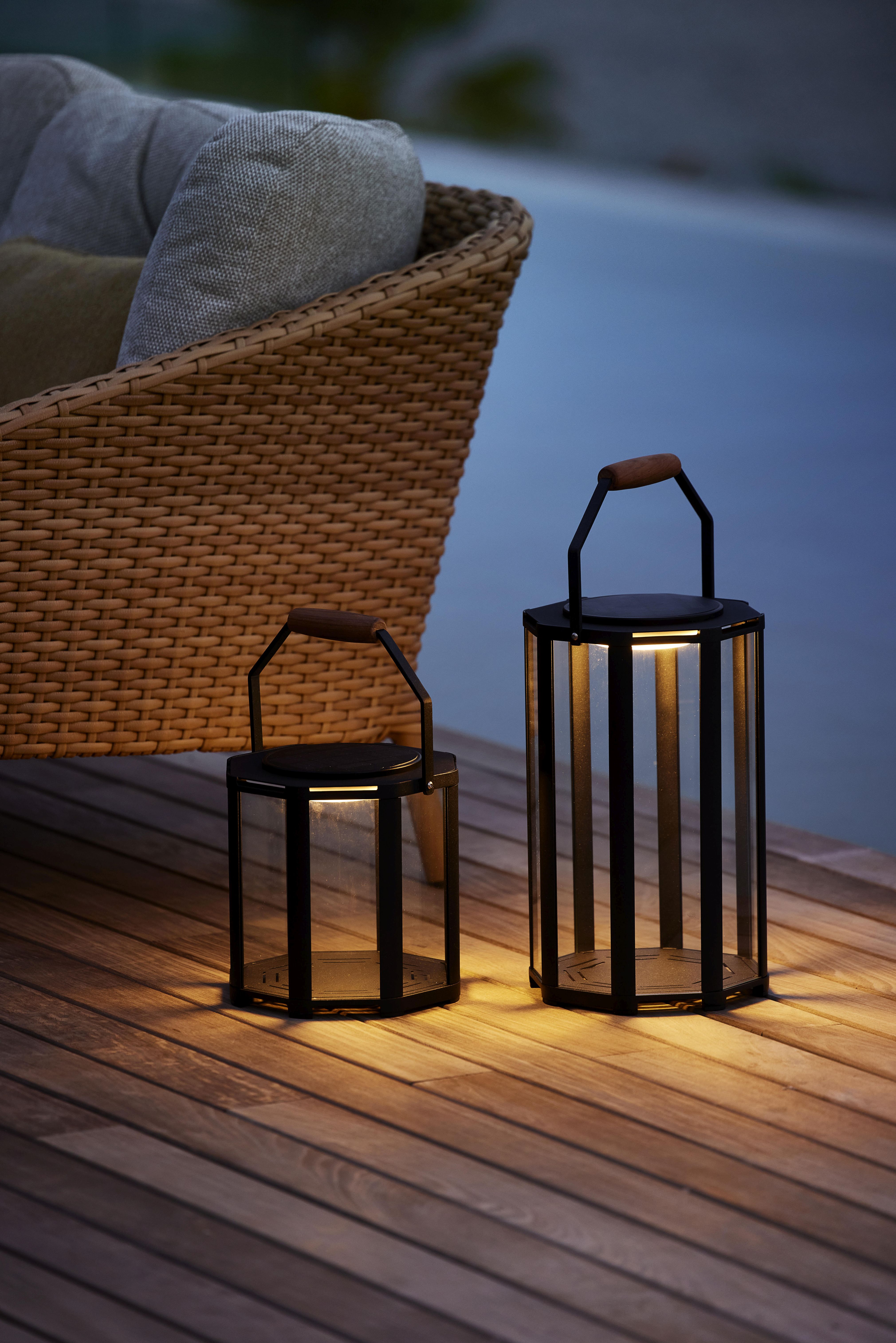 Zwei Cane-Line Lightlux Laternen aus Teakholz und Metall auf einer Holzterrasse.