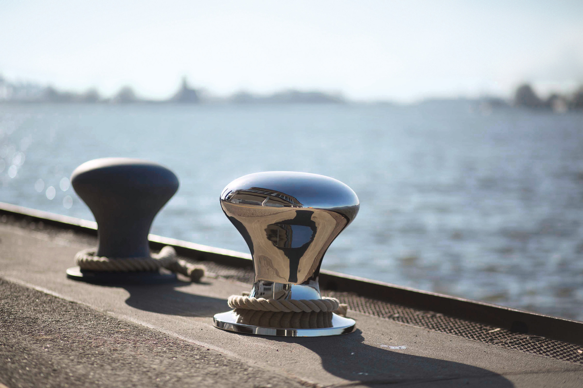Hamburger Hocker Philippi: Zwei Poller, einer aus Edelstahl, mit Seil am Wasser.