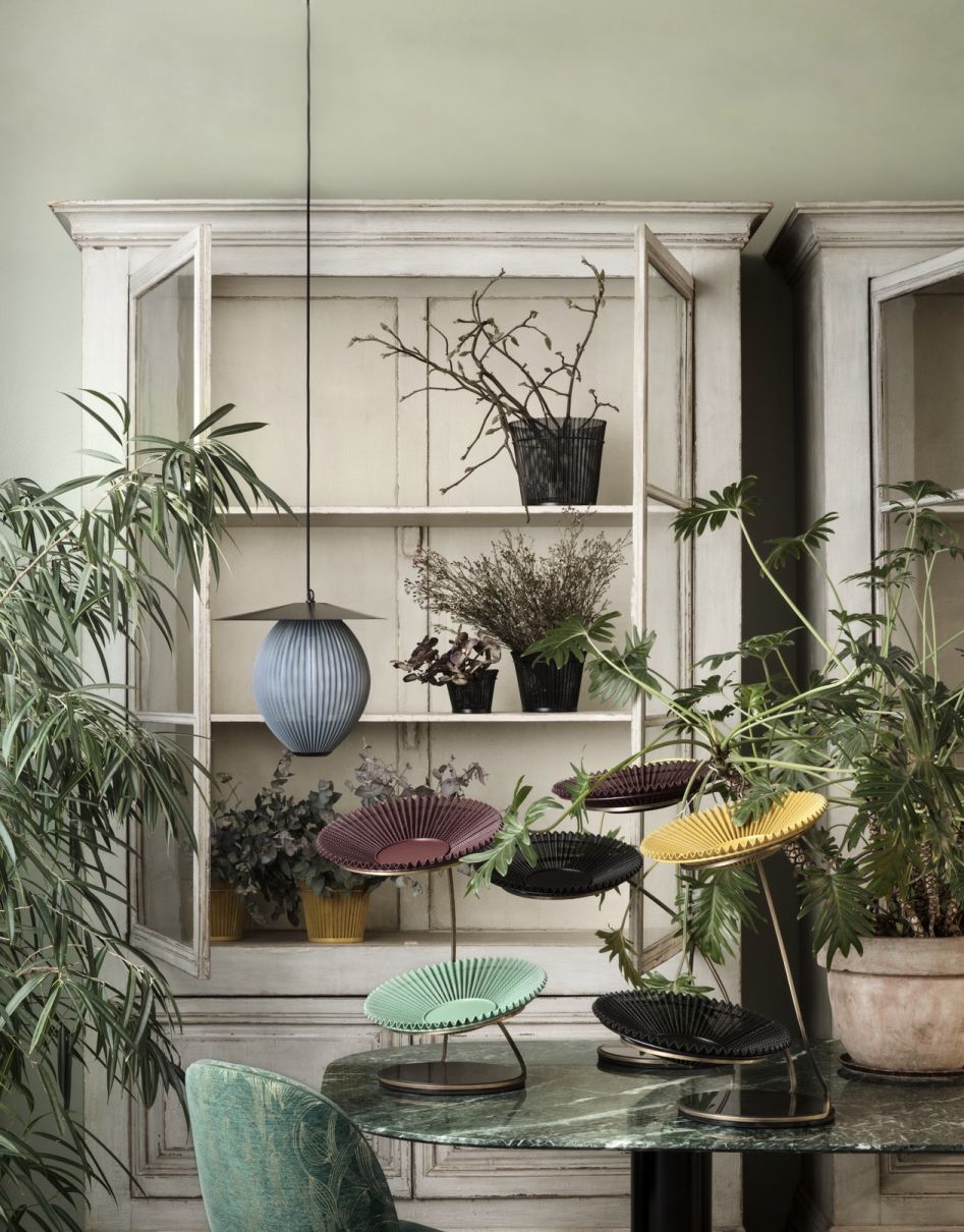 Verschiedenfarbige Matégot Schalen von Gubi auf einem Tisch, dekorative Inneneinrichtung mit Pflanzen und Schrank.