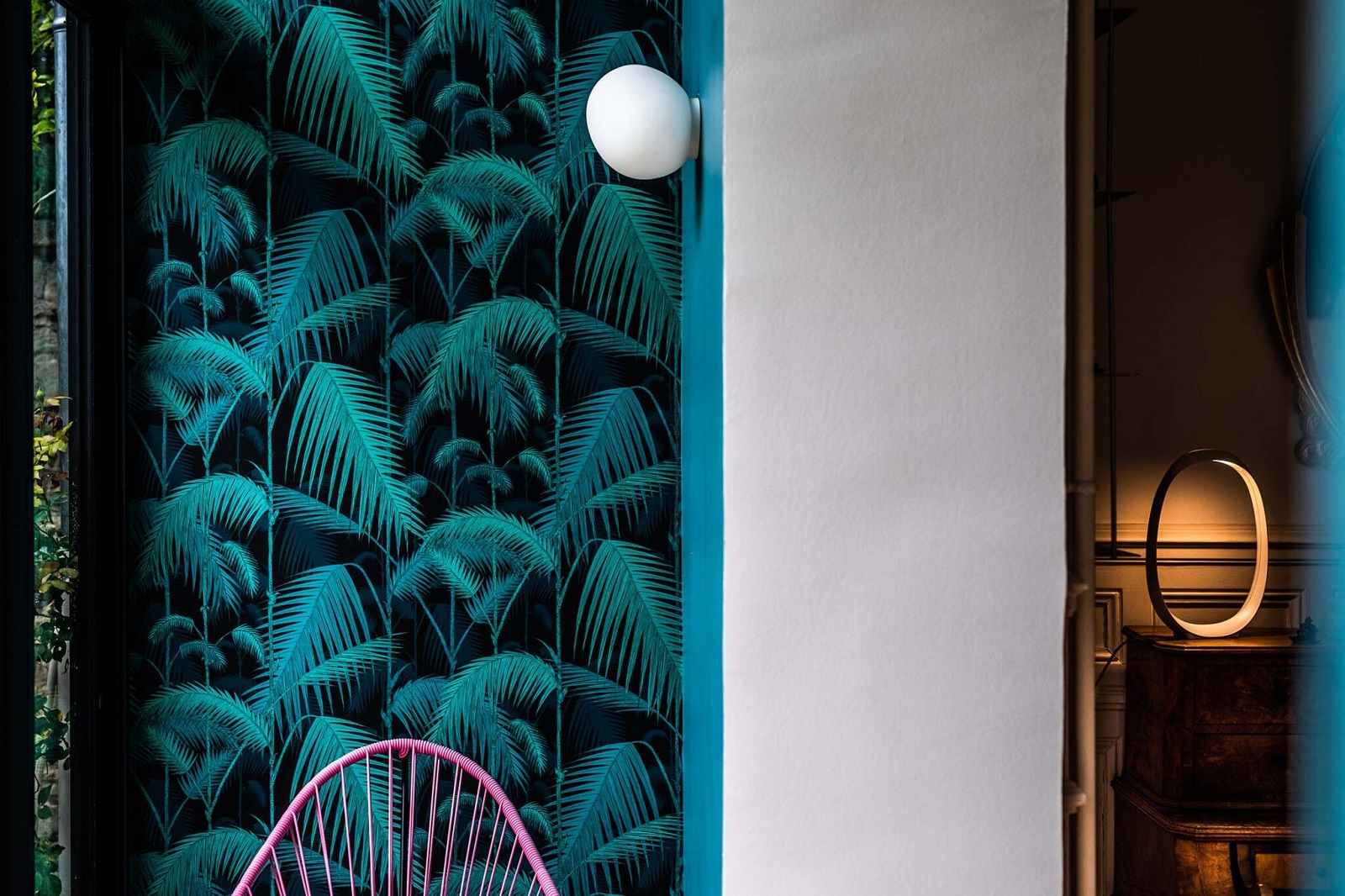 Weiße Gregg Wandleuchte von Foscarini an Wand mit tropischem Palmenmuster. Moderne Innenraumbeleuchtung.