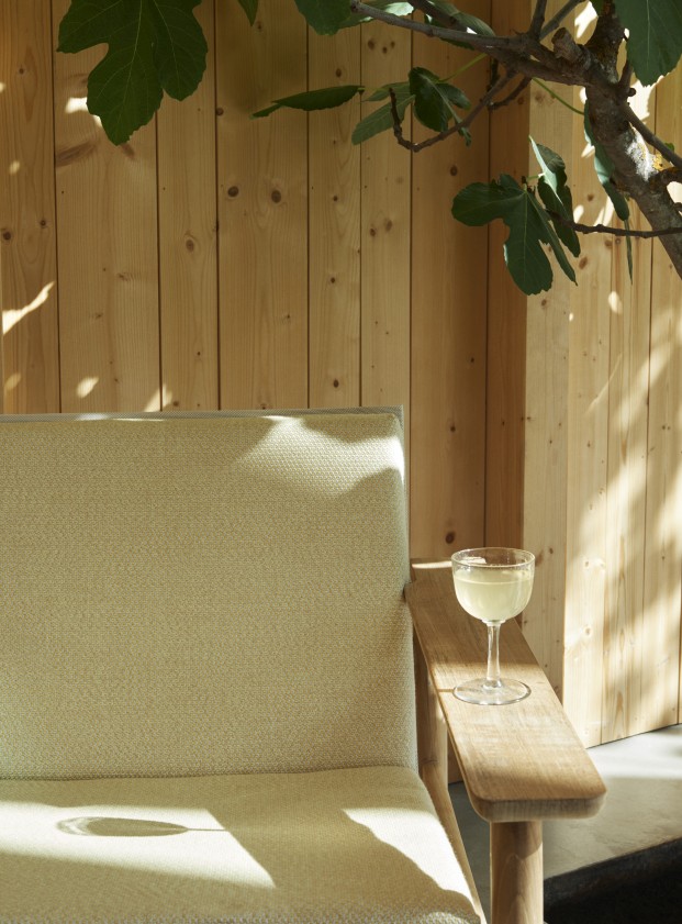 Nahaufnahme des Pelagus Lounge Sessels von Skagerak mit Getränk im Freien.